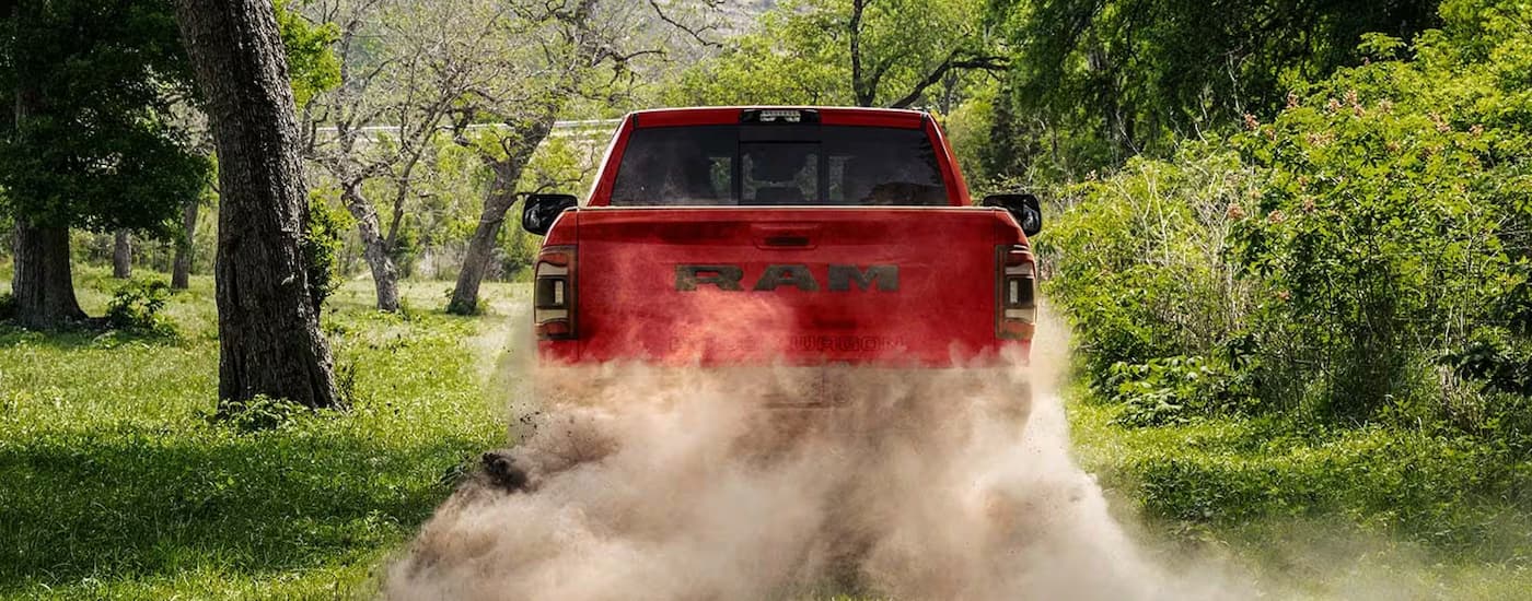 A red 2023 Ram 2500 Power Wagon is shown from rear while driving on a dusty dirt road.