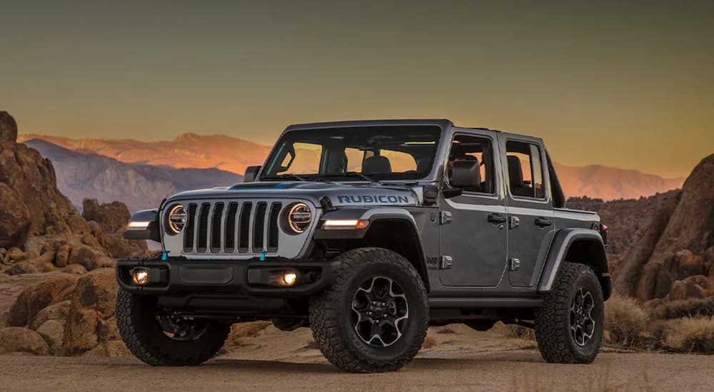 A silver 2021 Jeep Wrangler 4xe parked in front of desert mountains.