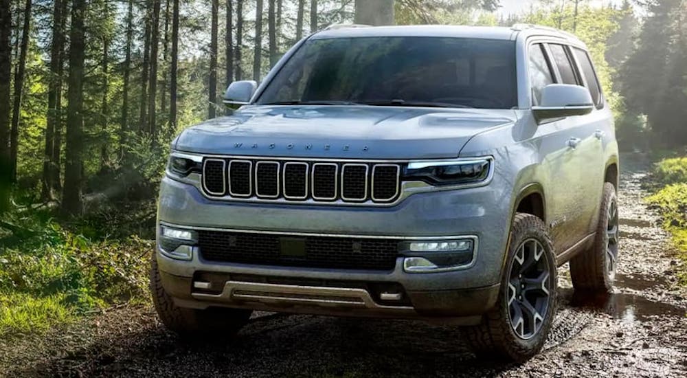 A silver 2022 Grand Wagoneer off-roading on a muddy trail in the woods after leaving a New Jersey Jeep dealer.