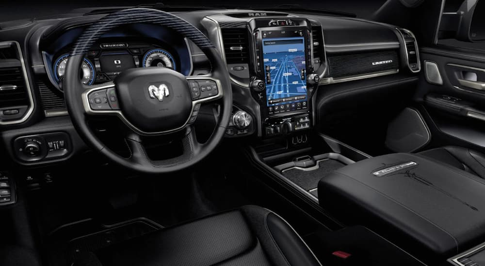 The black interior of a 2021 Ram 1500 showing the steering wheel and infotainment screen.
