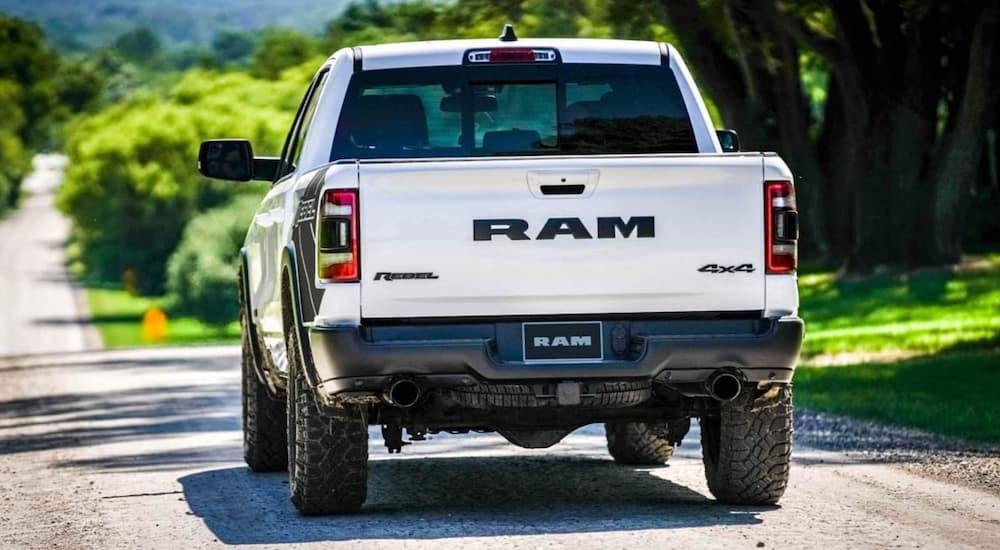 Rear view of a white 2021 Ram 1500 driving on an open road.