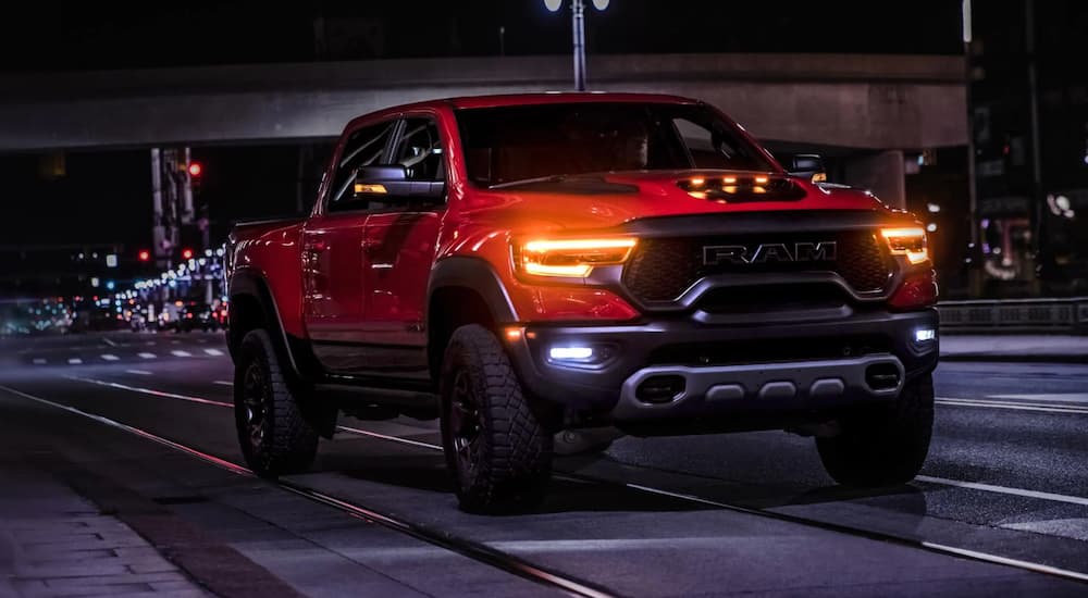 A red 2022 Ram 1500 TRX is shown from the front driving through a city at night after leaving a New Jersey Ram 1500 dealership.