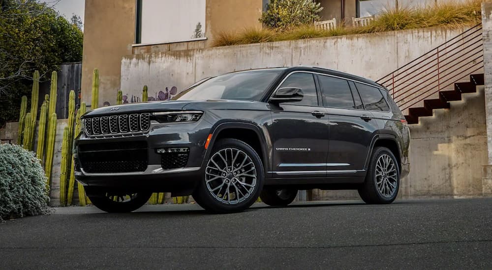 A silver 2022 Jeep Grand Cherokee L is shown parked outside of a modern home.