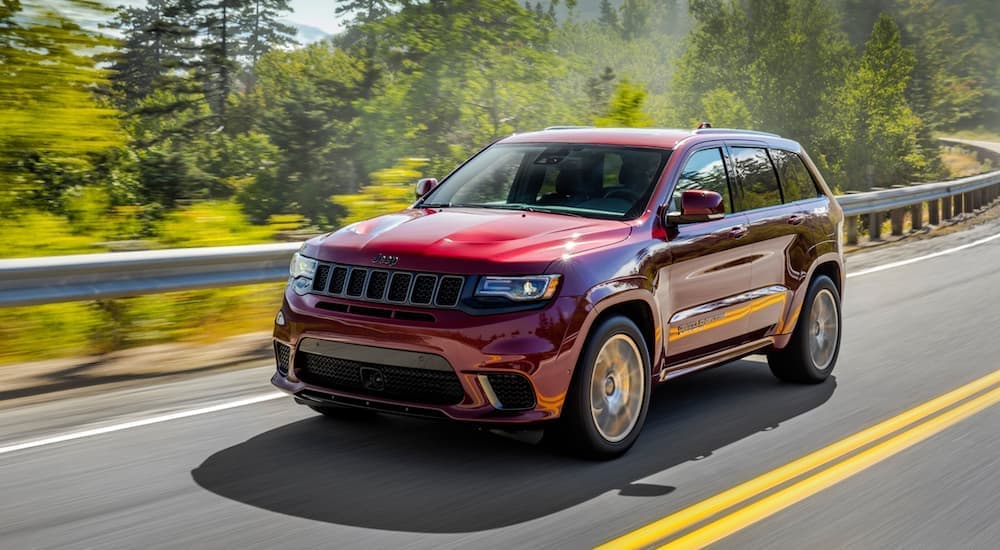 A red 2018 Jeep Grand Cherokee driving on a tree-lined road
