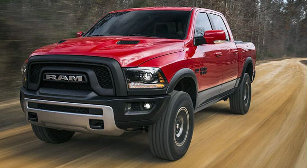 A red 2020 Ram 1500 Rebel driving on a dirt road in the woods.