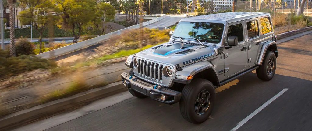 A silver 2022 Jeep Wrangle Rubicon 4xe Hybrid driving through a city after leaving a NJ Jeep Wrangler dealer.