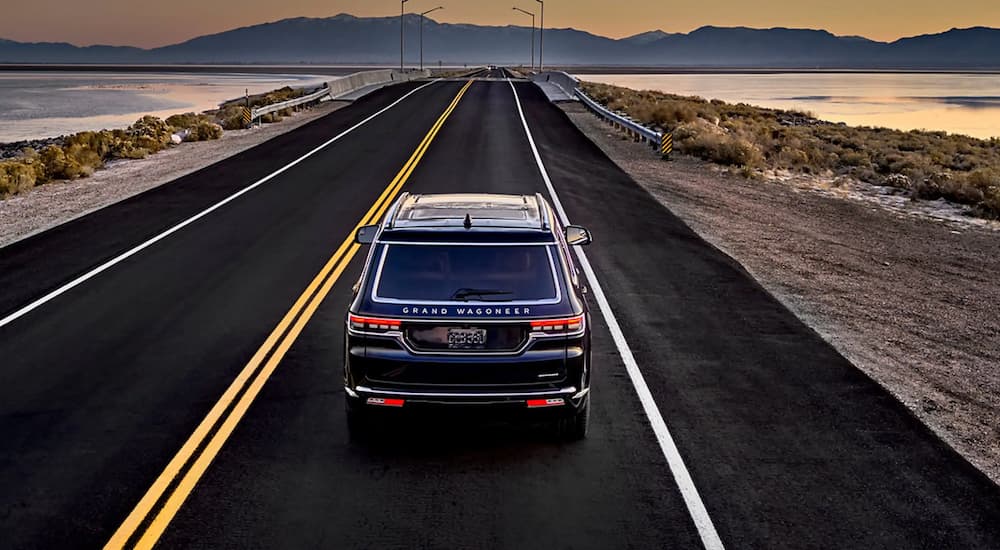 Overhead view of a black 2022 Grand Wagoneer driving on an open road along the coast.