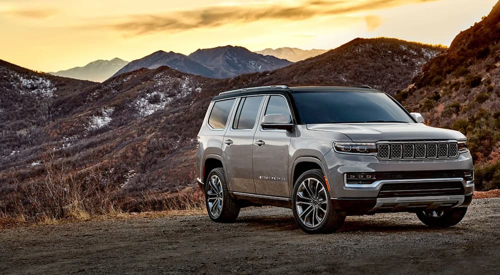 A silver 2022 Grand Wagoneer parked overlooking mountains at sunset.