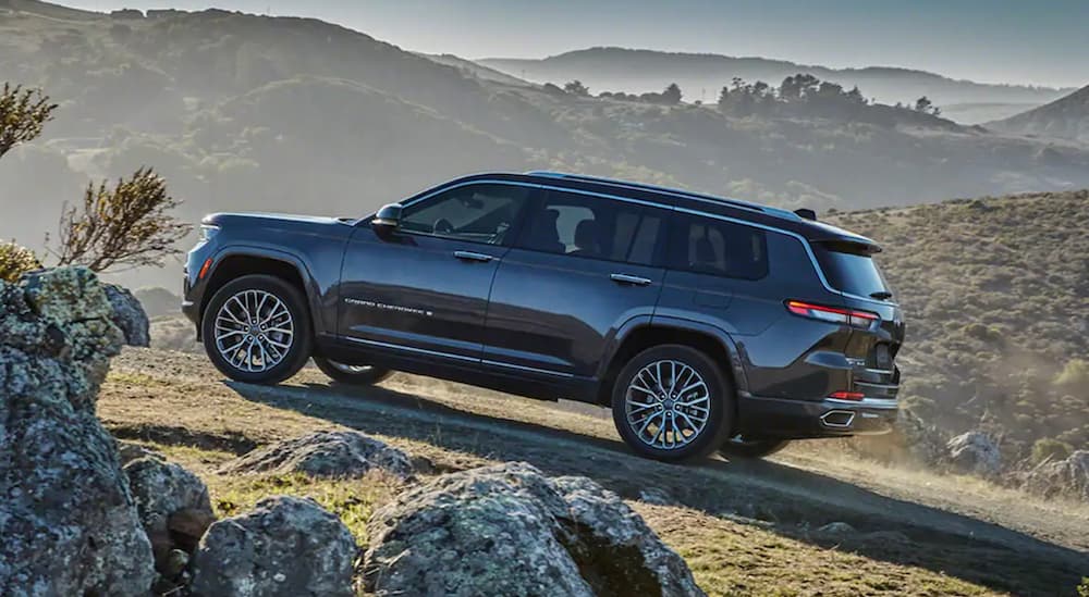 A grey 2022 Jeep Grand Cherokee L driving uphill while off-roading in the mountains.