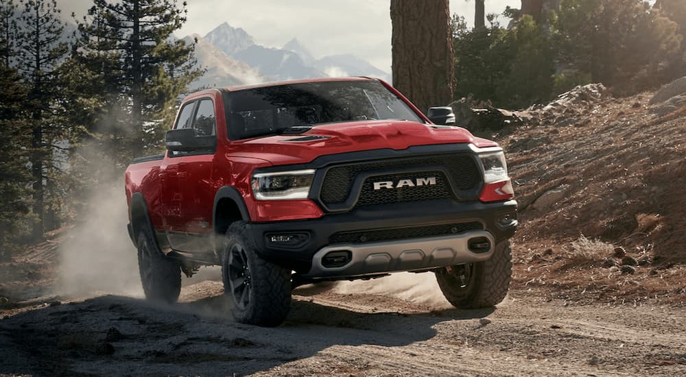 A red 2022 Ram 1500 Rebel driving on a dusty dirt road.