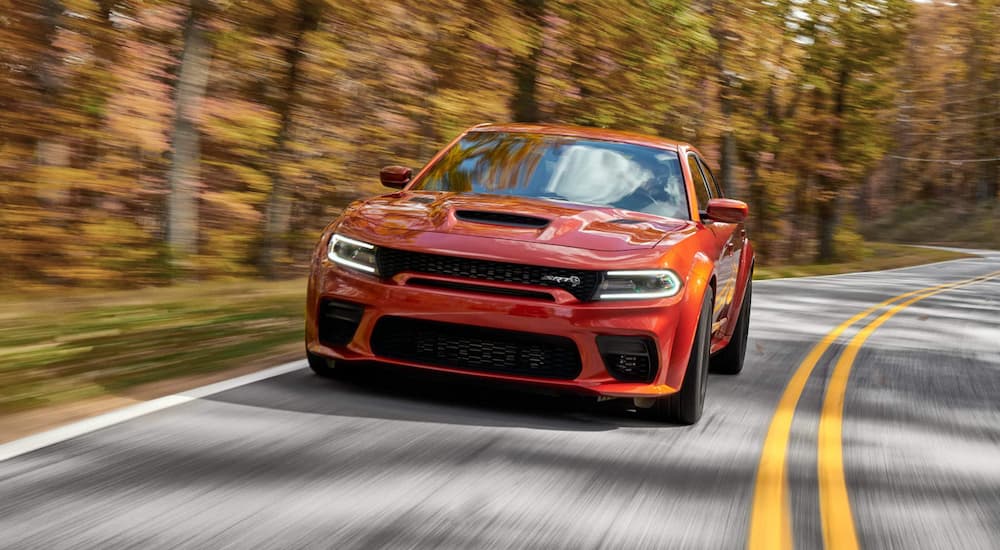 An orange 2022 Dodge Charger Hellcat driving on an open road.