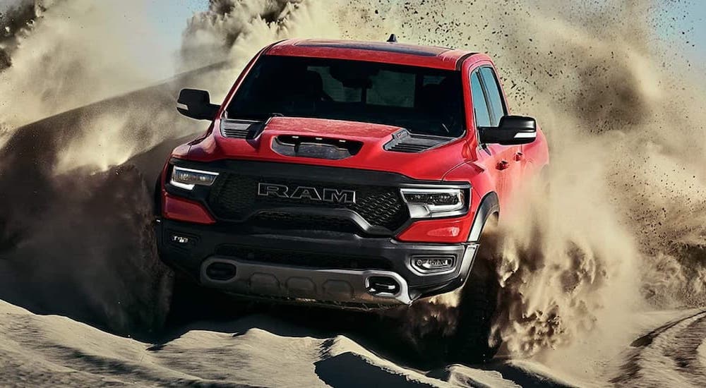 A red 2022 Ram 1500 TRX kicks up sand while off-roading on the beach