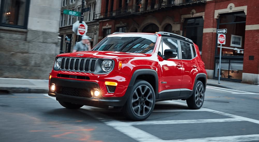 A red 2022 Jeep Renegade driving through a city intersection
