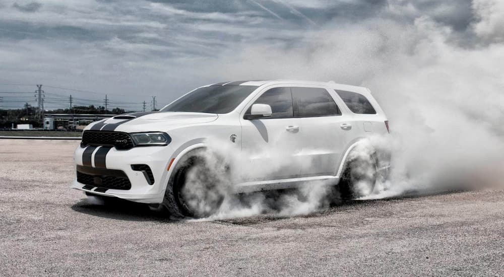 A white 2022 Dodge Durango Hellcat is shown from the side while performing a burnout.