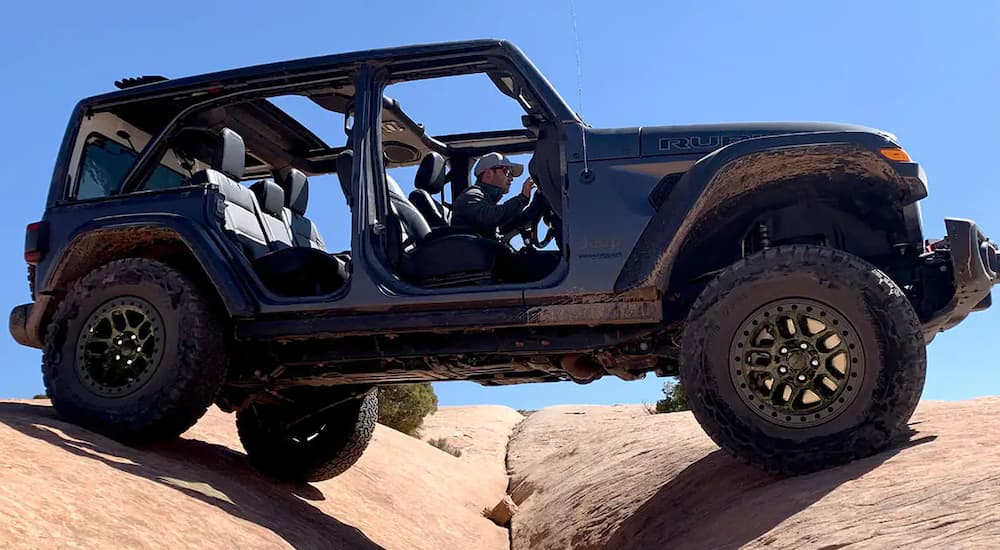A grey 2021 Jeep Wrangler Rubicon is shown from the side off-roading on a rocky trail.