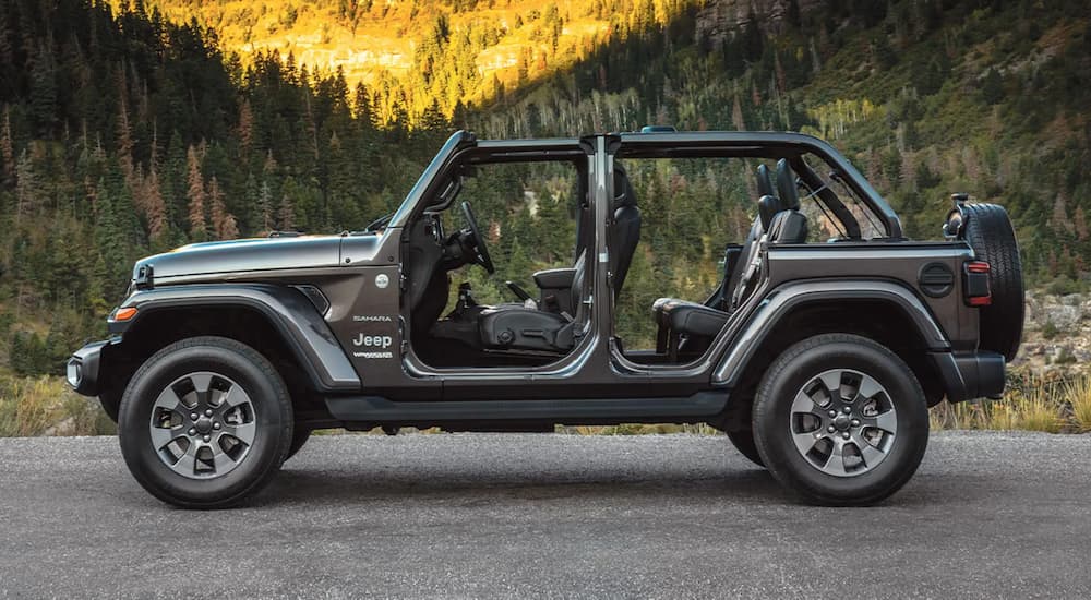 A grey 2022 Jeep Wrangler Sahara is shown from the side parked with the doors off.