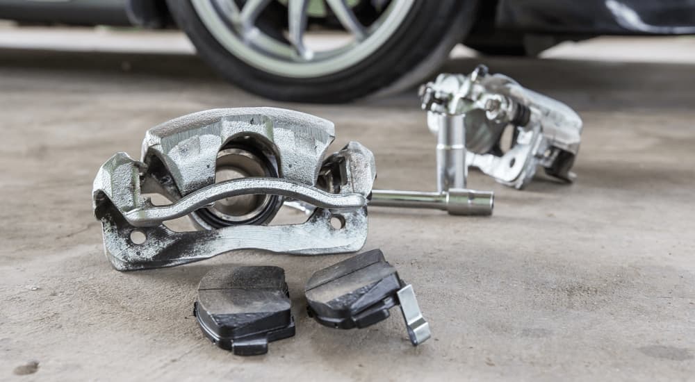 A close up of brake calipers on the floor of an auto repair shop.