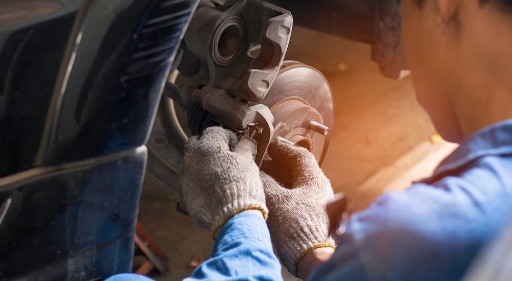 A mechanic putting a set of brakes together on a vehicle.