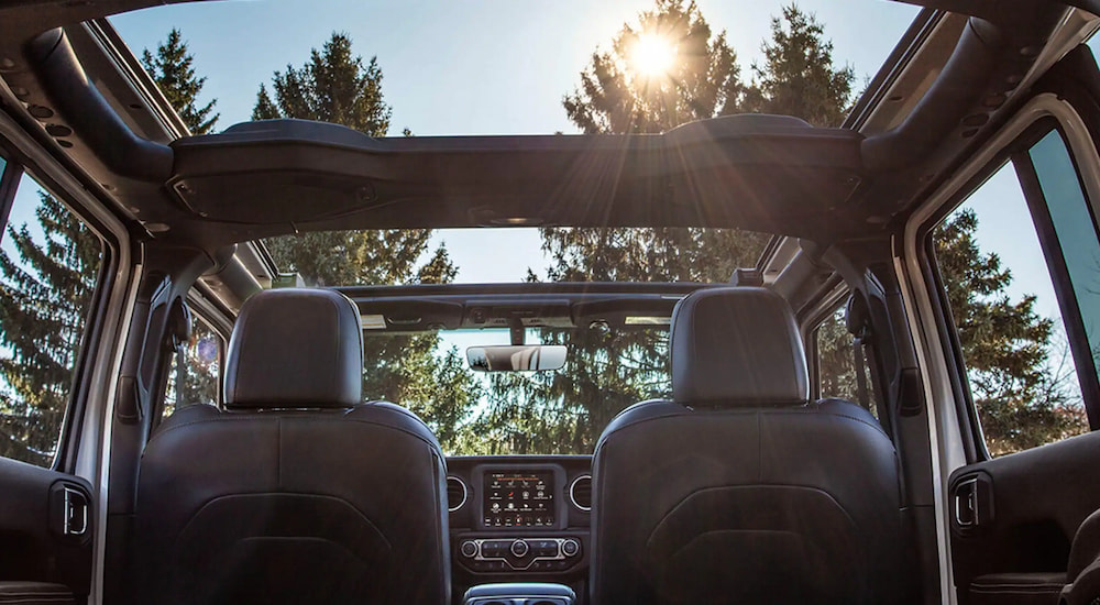 The interior and open roof of a 2023 Jeep Wrangler, seen from the back seat.