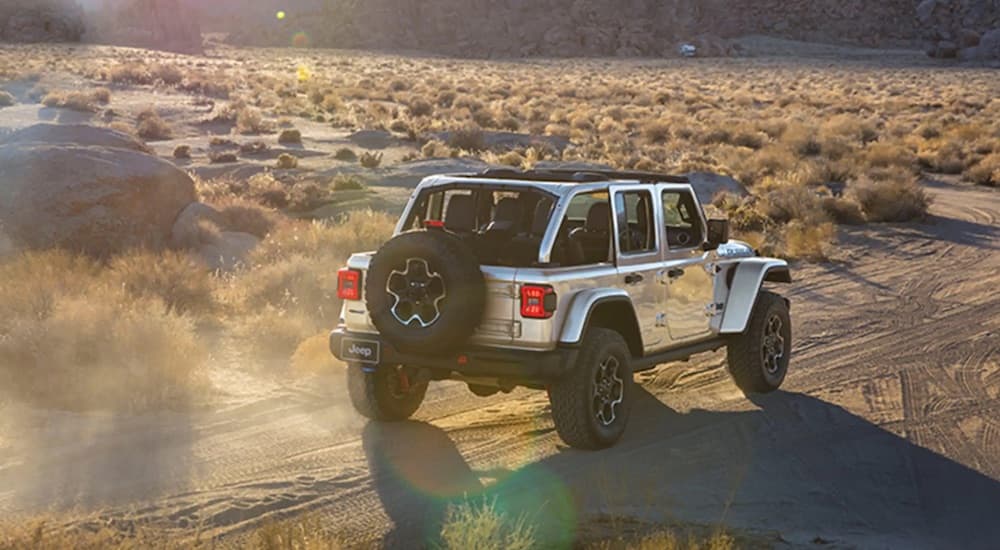 A silver 2024 Jeep Wrangler Rubicon 4xe driving on a desert trail.