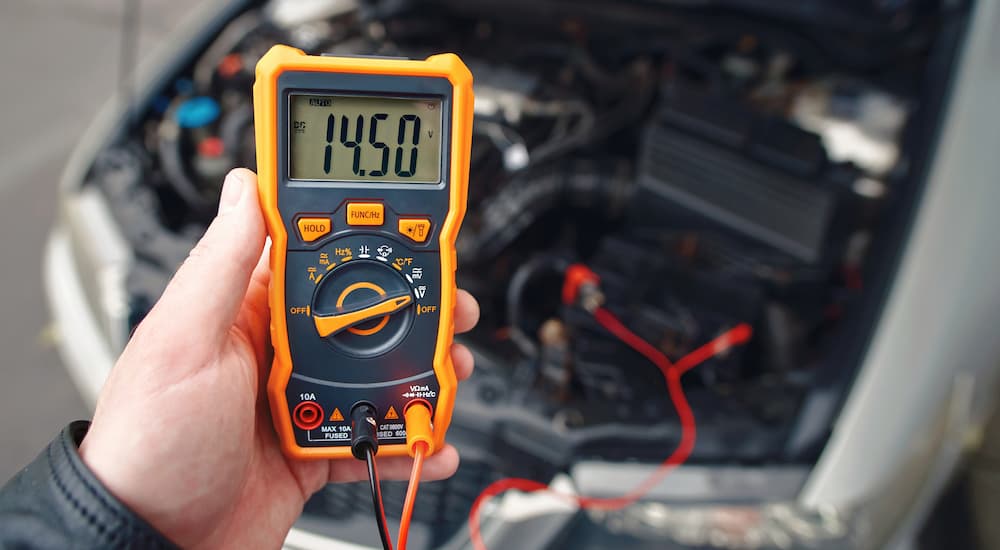 A mechanic is shown using an meter to check a car battery.