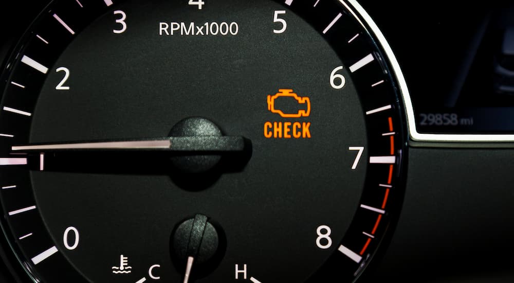 A close up of a dashboard and check engine light is shown.