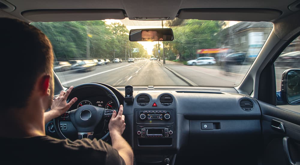 A person is shown driving their car on a city street to a car repair appointment.