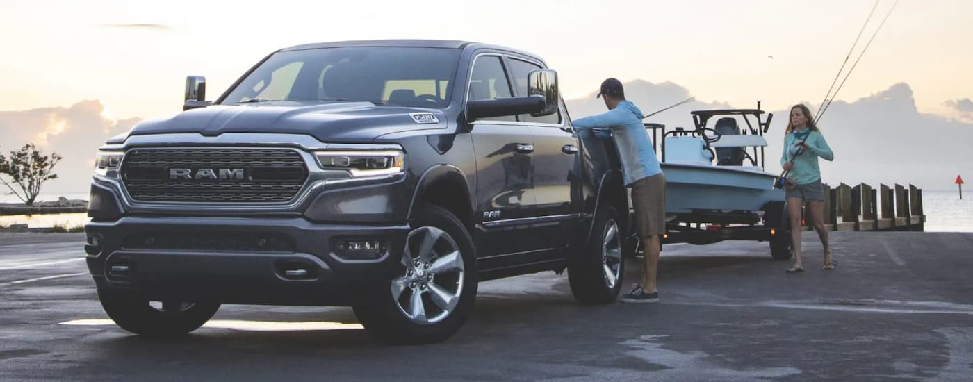 A grey 2021 Ram 1500 is towing a boat on a jetty after leaving a Ram dealership in NJ