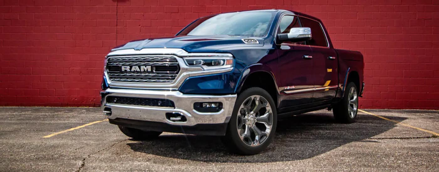 A blue 2021 Ram 1500 is parked in front of a red brick wall after leaving a Ram dealership in NJ