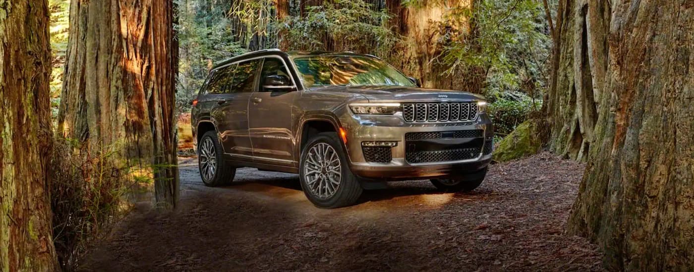 A tan 2021 Jeep Grand Cherokee L is parked in a forest.