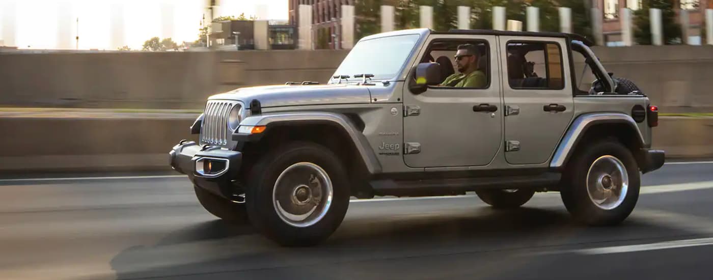 A silver 2021 Jeep Wrangler Unlimited is on the highway after leaving a Jeep dealer near me.