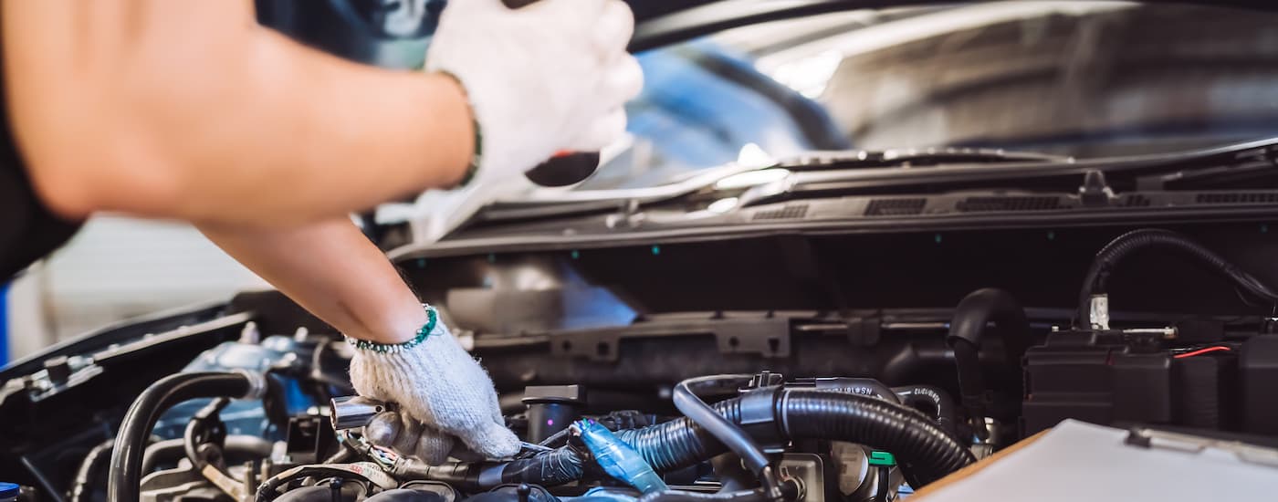 A close up of a mechanic inspecting an engine of a vehicle.