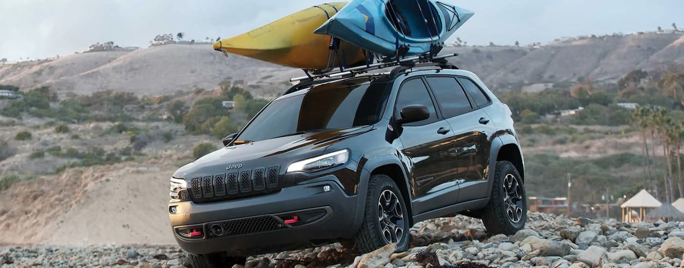 A black 2022 Jeep Cherokee is shown off-roading over rocks.