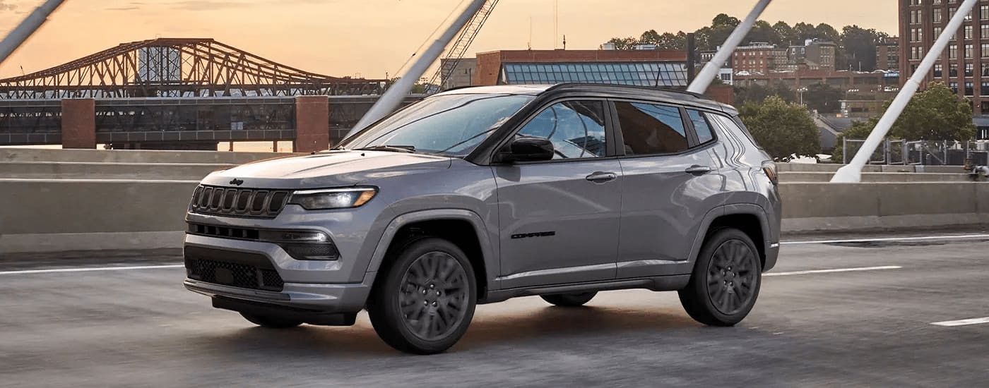 A grey 2022 factory order Jeep Compass is shown driving in a city.