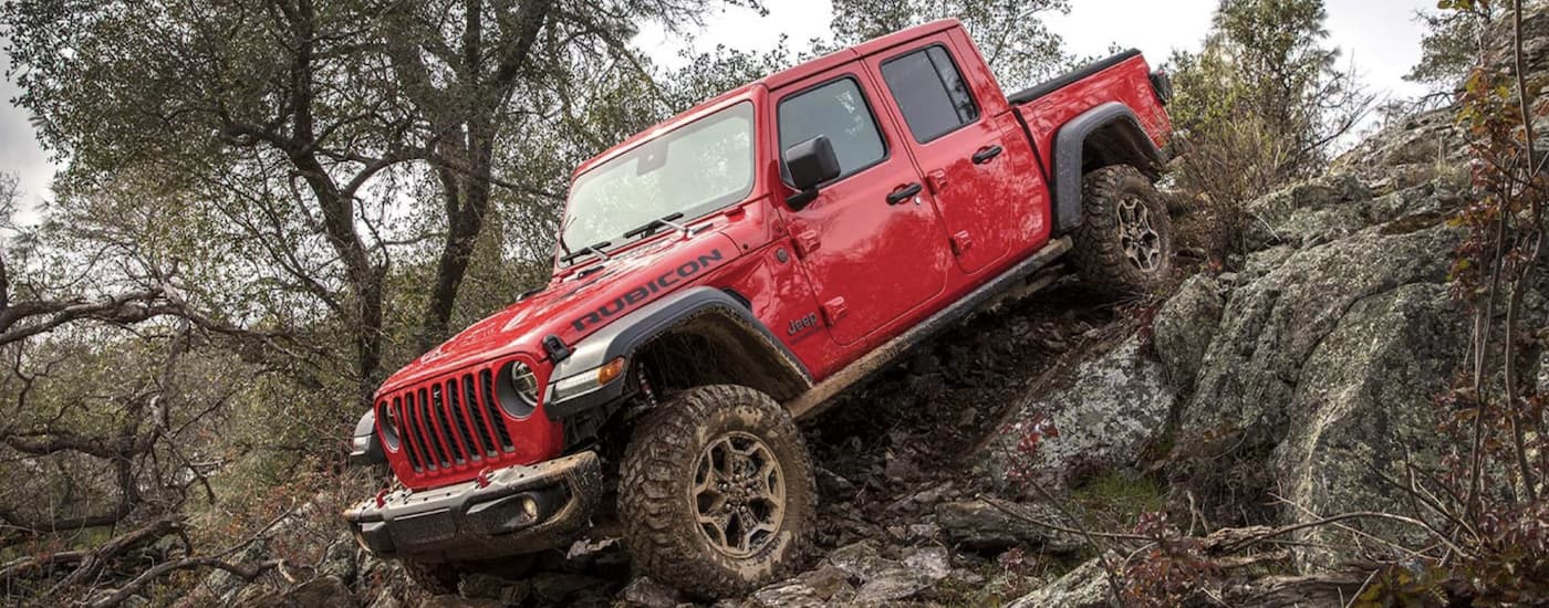 A red 2022 Jeep Gladiator is shown off-roading in the mountains