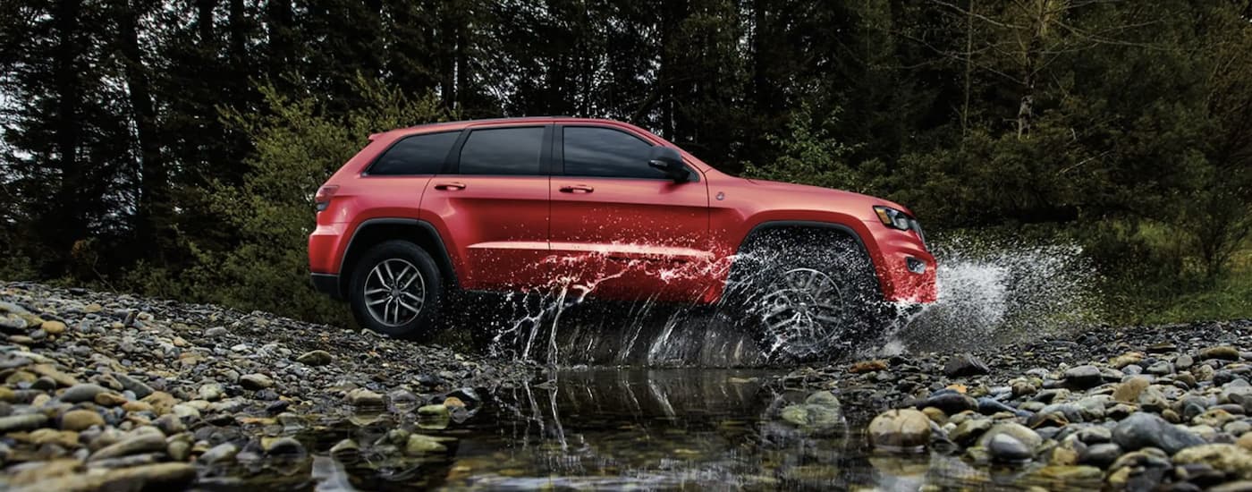 A red 2022 Jeep Cherokee is shown from the side crossing a river after leaving a Glassboro Jeep dealer.