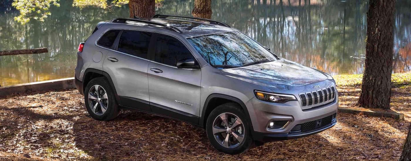 A silver 2022 Jeep Cherokee is shown parked next to a pond.