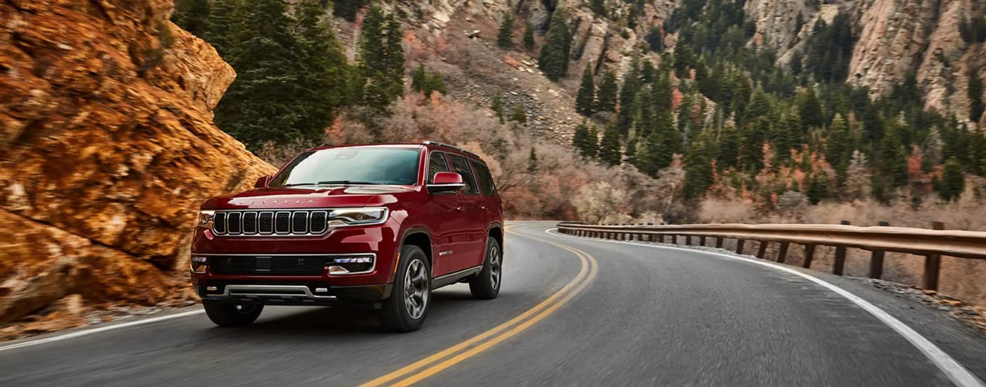 A red 2022 Wagoneer is shown driving on an open mountain highway.