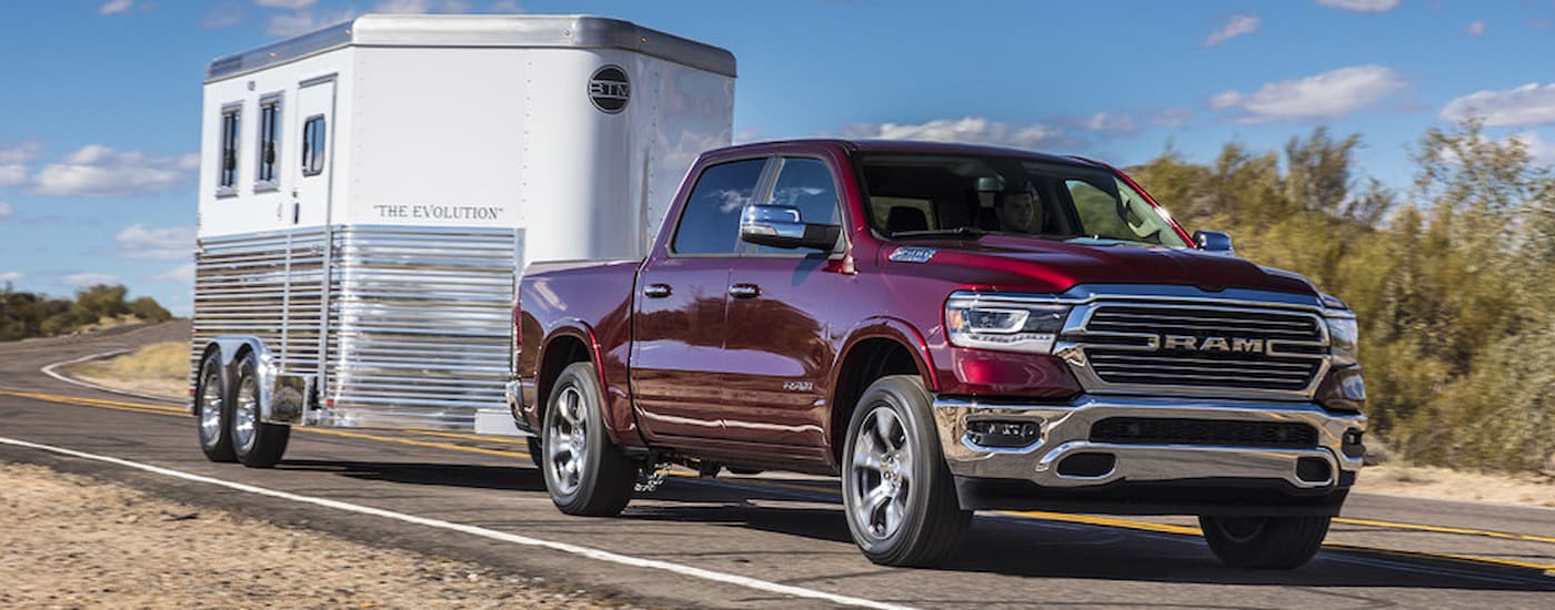 A red 2022 Ram 1500 Laramie is shown towing a white trailer.