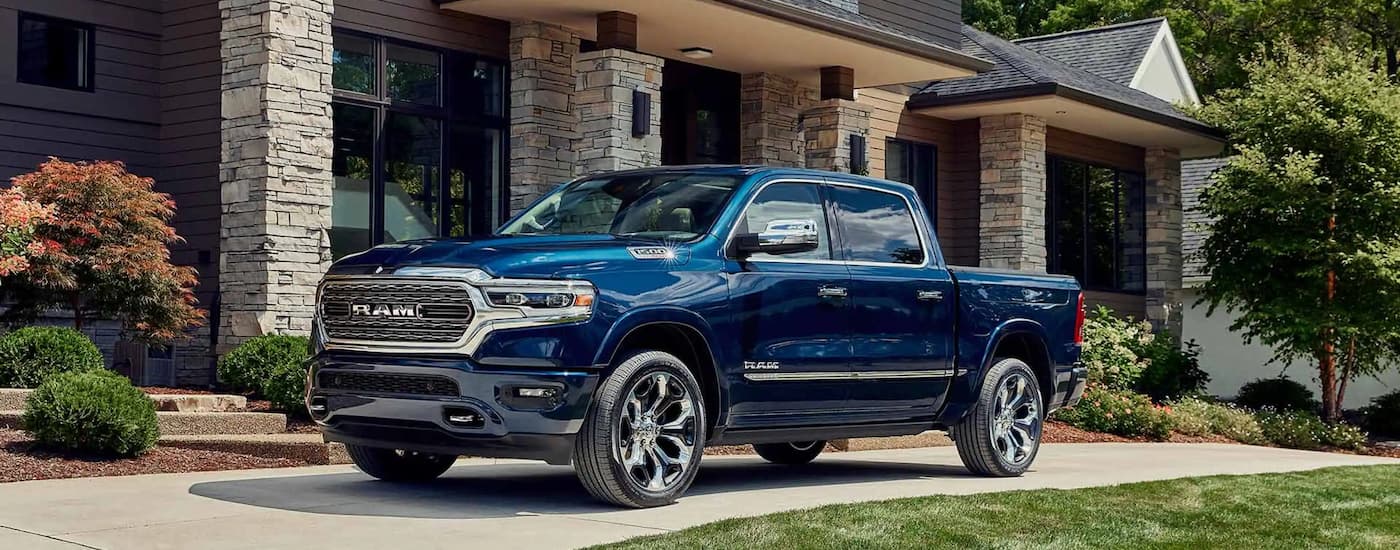 A blue 2023 Ram 1500 is shown from the side parked on a driveway.